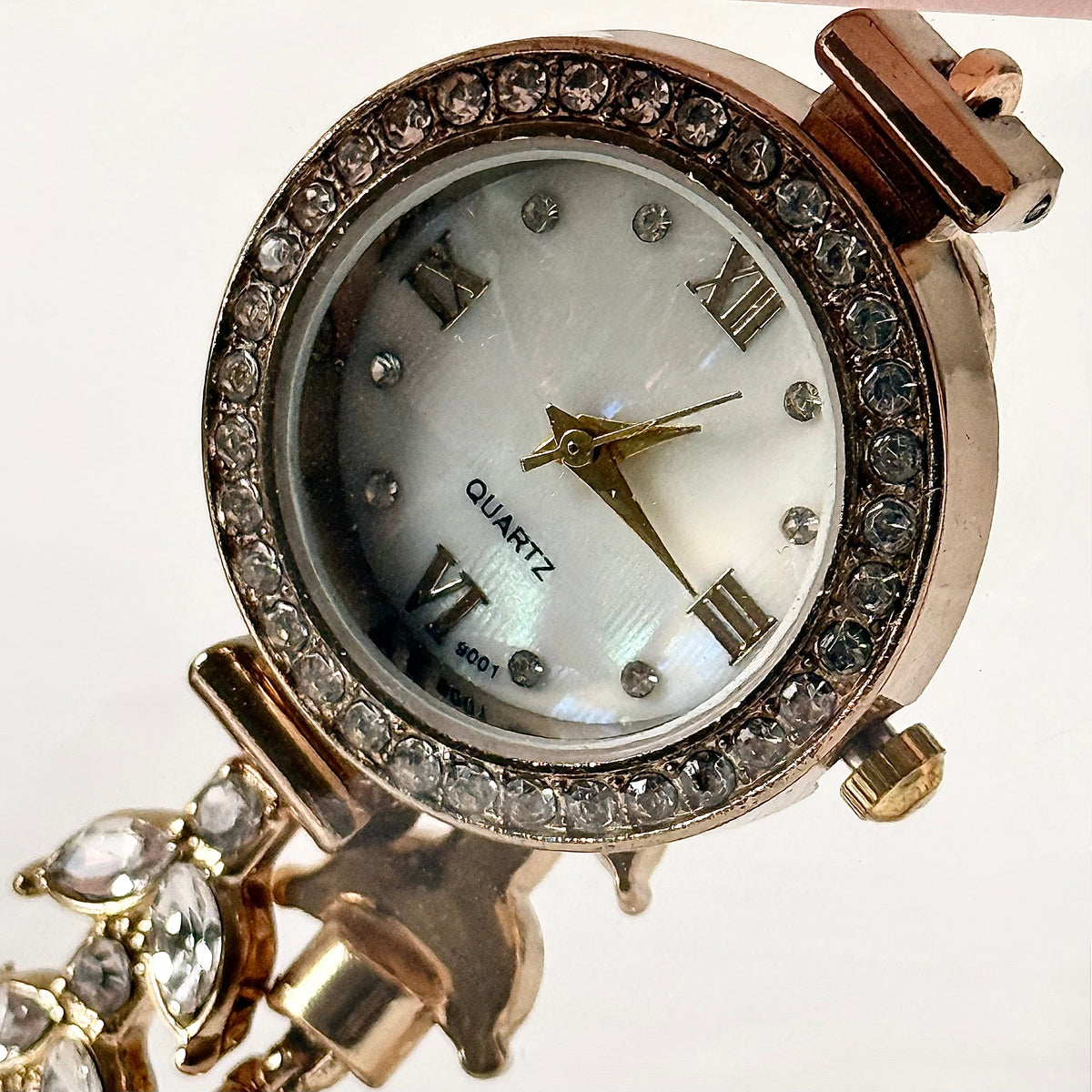Gold crystal bezel watch close-up showing mother-of-pearl dial