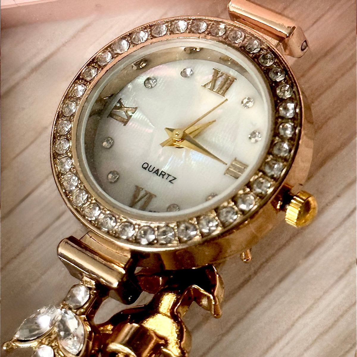 Gold crystal bezel quartz watch close-up on wooden surface