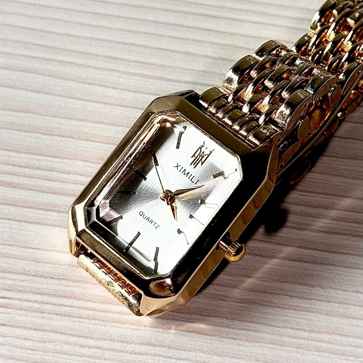 Gold rectangular quartz watch flat lay on wooden surface
