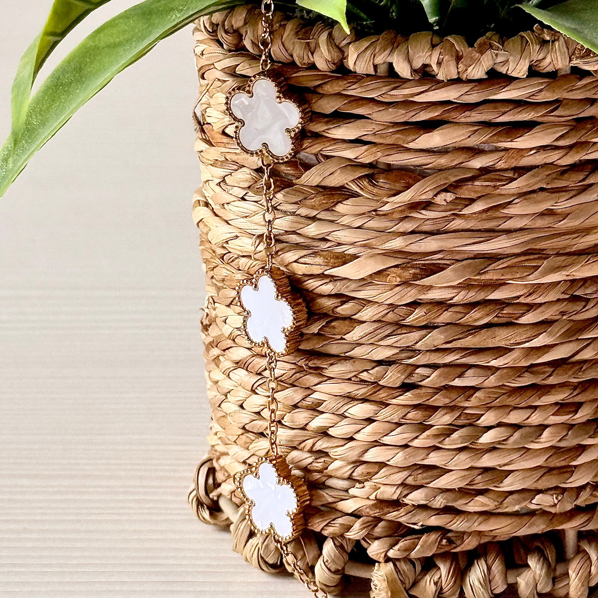 Gold clover charm bracelet draped on woven basket