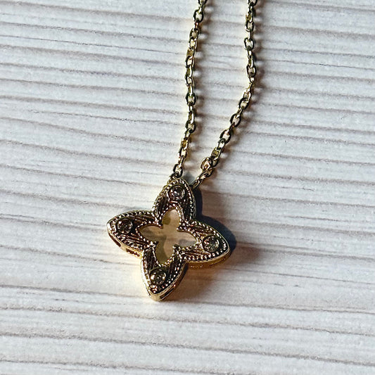 Gold filigree flower pendant necklace close-up on white surface