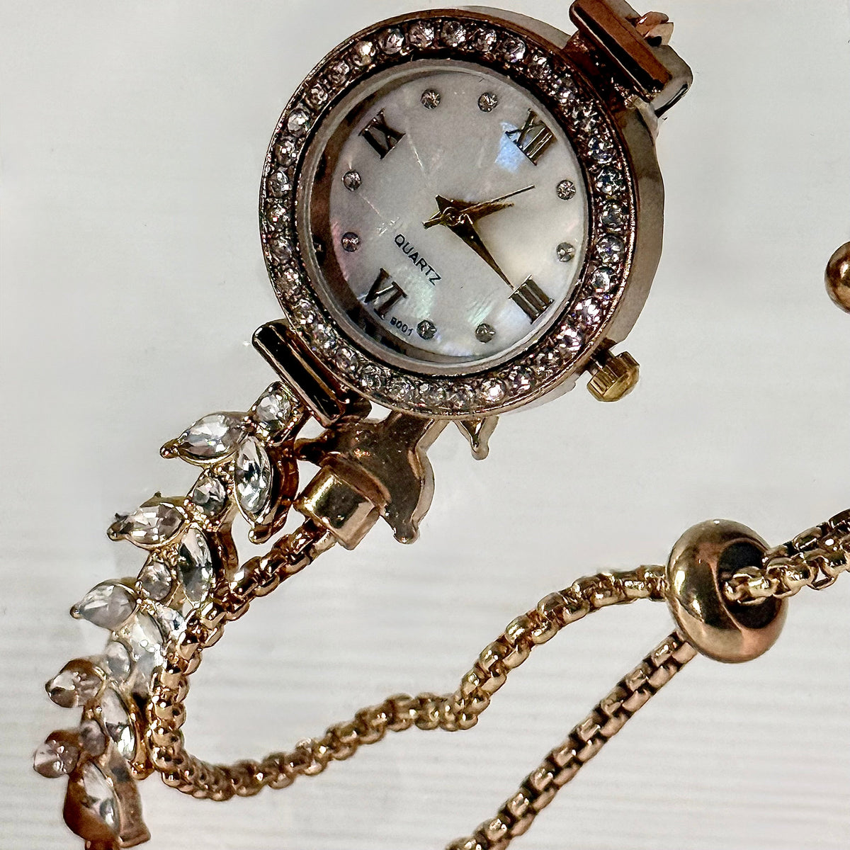 Gold crystal charm bracelet watch laid flat showing strap detail